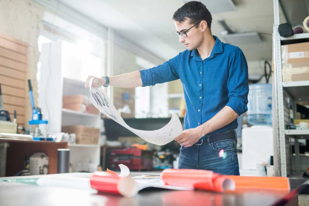 Man looking at printed poster designed